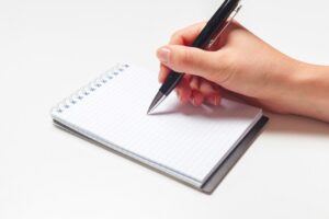 Person writing on memo pad
